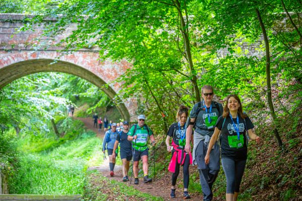 Walkers doing the Cotswold Way challenge along a canal on a sunny day